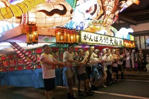 Volunteers pulling a float during a festival. Banner reads 'Gambarou Ofunato.' Photo courtesy of Grace. 